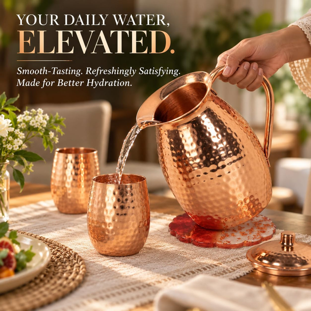 Water being poured from the hammered copper pitcher into a matching copper tumbler on a table setting